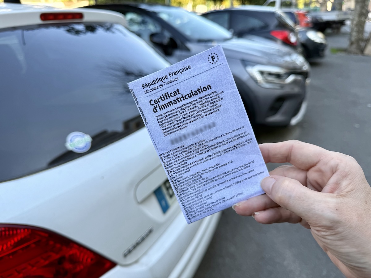 Carte grise devant une rangée de voitures